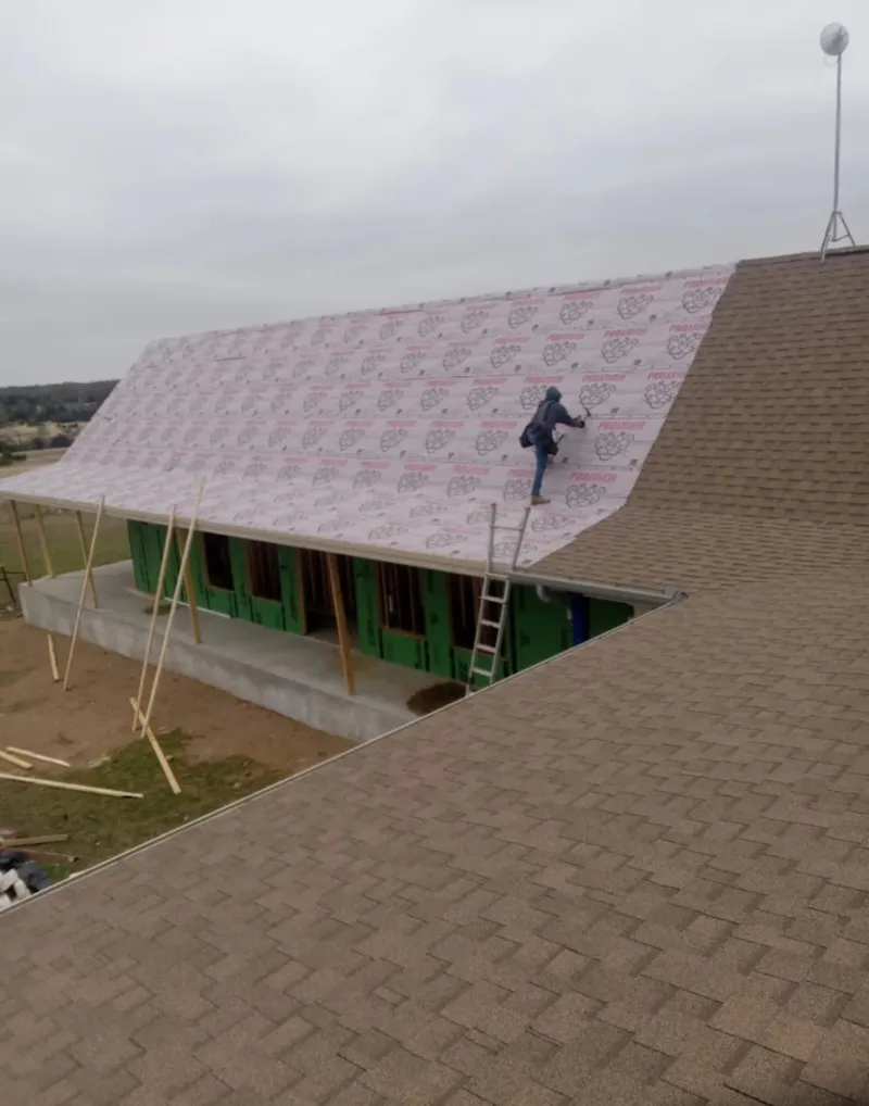 Worker preparing underlayment for a metal roof installation in Sandy Oaks